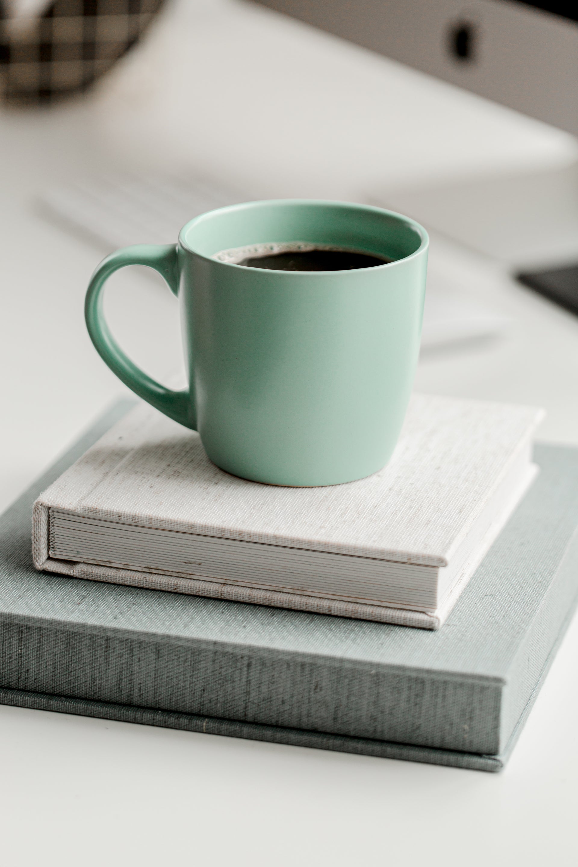 mint coloured coffee cup on a table with two books