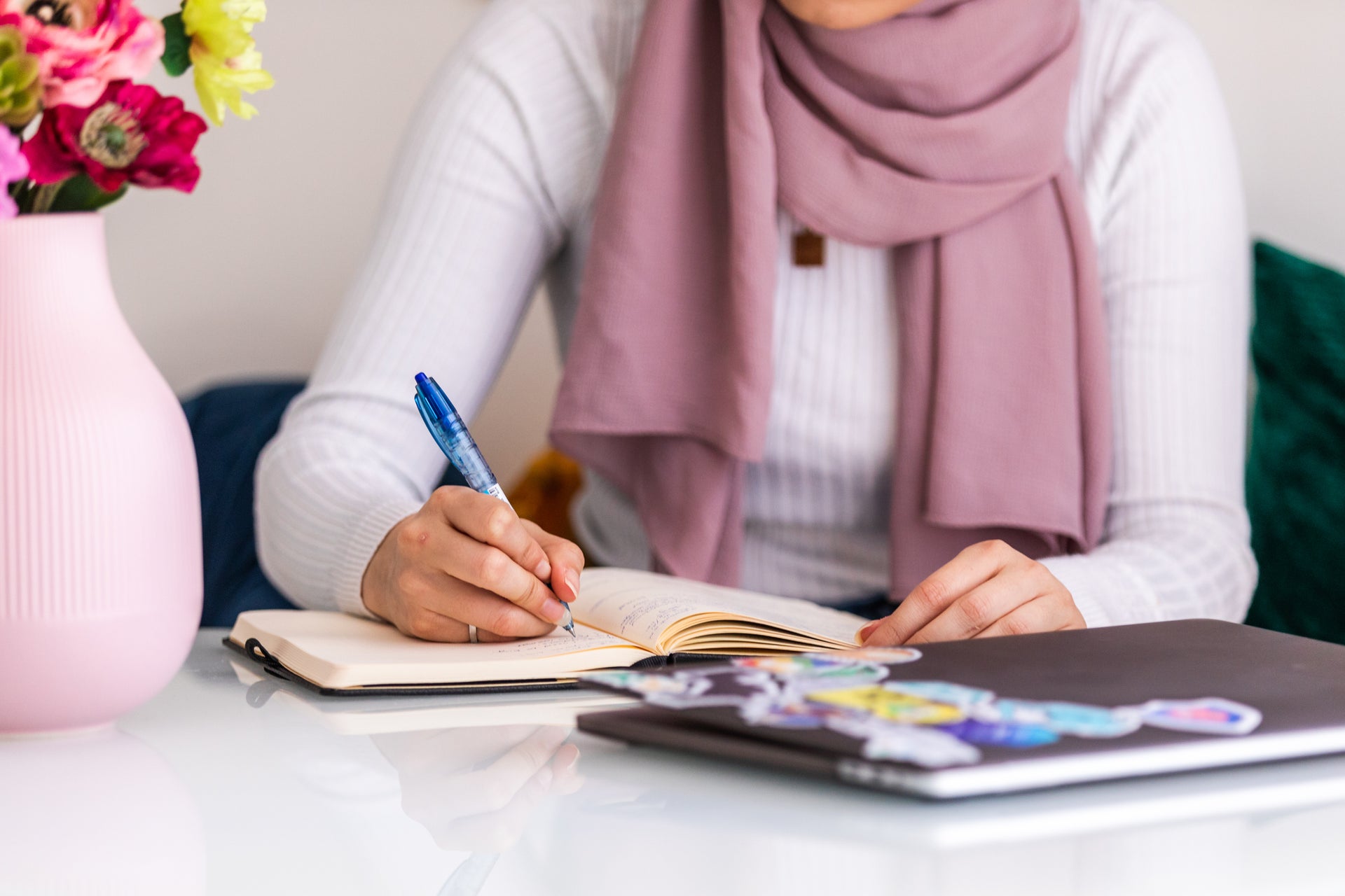 woman sat at a table writing in a journal